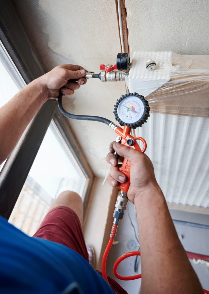 Male plumber checking gas tightness of heating system.